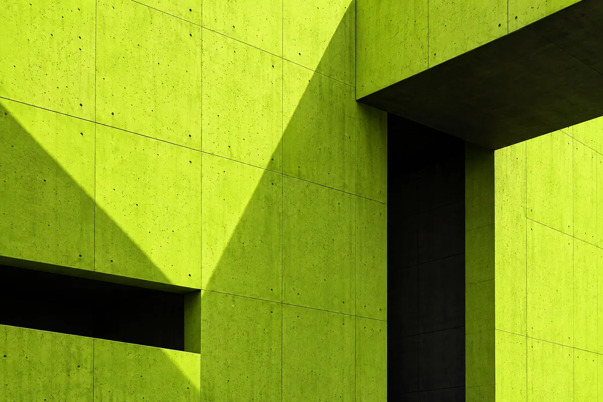 Arquitectura de hormigón verde lima con volúmenes y sombras profundas.